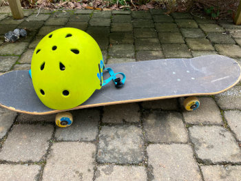 Ein leuchtend-grüne Helm liegt auf einem Skateboard